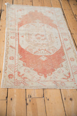Angled perspective of a distressed Oushak rug, emphasizing the faded rust medallion and low pile.