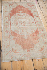 Full length perspective view of a distressed vintage Oushak rug with faded rust tones.