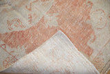 A folded corner reveals the hand-knotted foundation and distressed pile of a Turkish Oushak rug.