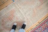 Low-pile texture of a distressed vintage Oushak rug showing time-softened blush and sandalwood tones.