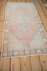 Textured pile of a distressed Oushak rug, showing cantaloupe, coffee, and blue tones, with intact side selvage.