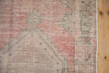 Distressed texture of a Vintage Oushak rug with faded raspberry and silver serrated pattern.