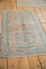 Angled view of a distressed Oushak rug featuring a faded teal tree of life on a saffron field.