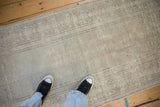 Textured, low pile of a distressed vintage Oushak rug with a faded geometric border in silver and pale green.