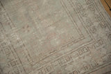 Textured, low pile of a distressed rug showing mostly even wear in silver and green hues.