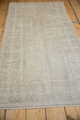 Low angle view of a distressed Oushak rug, showing its worn texture and silvery open field.