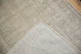 Folded corner of a vintage Oushak rug showing its tight hand-knotted back and low pile texture.
