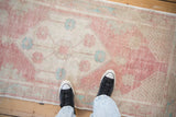 Distressed Oushak runner close-up, with faded raspberry, ivory, turquoise floral motifs and worn pile.