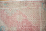 Distressed Oushak rug pile showing faded raspberry, ivory, and hints of sea foam green.