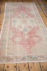 Vintage distressed Oushak rug runner with faded raspberry red field, ivory guls, and geometric vine border.