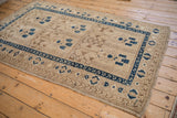 Distressed vintage Afghani rug: ivory panels and dark sapphire blue geometric border.