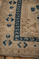 Distressed Afghani rug detail: sapphire blue geometric border and sand field with visible wear.
