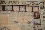 Textured Oushak rug pile with stepped geometric border in mauve, dusty blue, and chocolate brown.