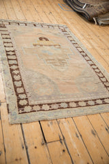Distressed Vintage Oushak rug corner, showing worn pile, chocolate brown border, and fringe.