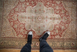 Distressed vintage Anatolian rug with faded red and antique ivory oversized medallion, softened patina.