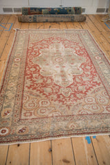 Distressed Anatolian rug, angled view of faded red arabesques with time-softened silver and ivory.