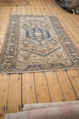 Worn end of a distressed vintage Hamadan rug with short fringe and beige.