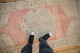 Distressed vintage Oushak rug displaying abrashed blush, seafoam green, and pale coffee floral motifs.