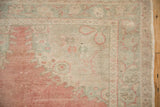 Distressed vintage Oushak rug's hand-knotted pile with faded blush and seafoam patterns.