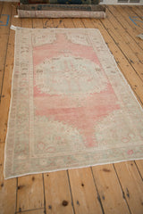Distressed vintage Oushak rug edge showing time-softened blush pink and seafoam green pile.