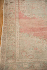 Abrashed field and border of distressed Oushak rug, showing blush, seafoam, and coffee tones.