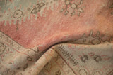 Distressed Oushak rug detail: blush, seafoam, and pale coffee brown pile with even wear.