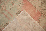 Distressed Oushak rug corner showing seafoam green, blush pink pile and woven foundation.