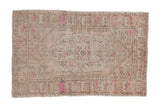 Vintage distressed Oushak rug with a floral medallion on a sandy beige field with fuchsia accents.