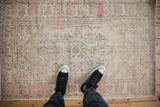 Time-softened low pile of a distressed Oushak rug with fuchsia and sand tones seen from above.