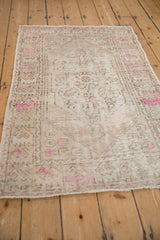 Side view of the vintage distressed rug showcasing its time-softened texture and bright pink accents.