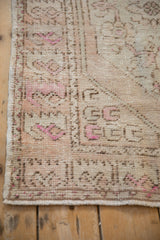 Detailed view of a distressed Oushak's worn pile, showing the intact side cord and fuchsia accents.