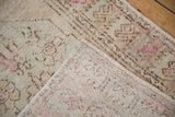 Folded corner of a vintage distressed Oushak rug showing the hand-knotted construction and worn pile texture.
