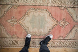 Distressed vintage Oushak rug runner, soft blush field, seafoam medallion, and worn pile.