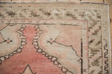 Distressed vintage Oushak runner corner showing dusty rose field, serrated leaf border, and even wear.