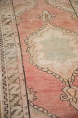 Distressed Oushak rug with scalloped medallion, blossomed floral finial, and serrated leaf border.