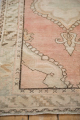 Distressed Oushak rug with scalloped medallion, dusty blush field, and serrated leaf border.
