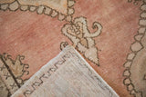 Distressed Oushak rug pile in dusty blush with ornate motifs and visible hand-knotted foundation.