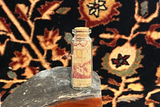 Hand-knotted antique silk rug fragment from a Tabriz carpet inside a collectible souvenir bottle.