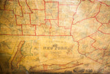 Aged canvas detail of an 1860 New York map featuring the title block and red county lines.