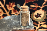 A souvenir bottle revealing the hand-knotted foundation of an antique rug fragment.