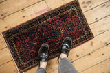 Antique Sarouk floral rug mat in raspberry red and navy blue, shown to scale from an overhead perspective.