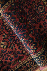 Lustrous wool pile of a fine antique Sarouk rug with red and sapphire blue blossoms.