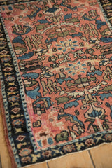 Inwardly directed floral palmettes and serrated leaves on the dusty rose field of an antique Lilihan rug.