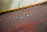 Reddish-brown antique wooden cabinet close-up, featuring brass concealed latch and numbered decorative plate.