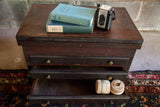 Open bottom drawer of the antique dark wood cabinet displaying two natural twine spools.