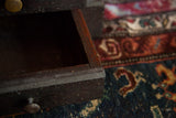 Open drawer of the antique wooden cabinet, revealing dark, aged wood texture.