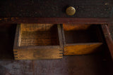 Open drawers of the antique wooden cabinet revealing warm wood and detailed dovetail joinery.
