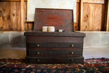 Antique dark wood cabinet, lid open, revealing three brass-knobbed drawers and interior.