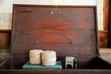 Dark reddish-brown interior of the antique wooden cabinet's open lid with metal hardware.