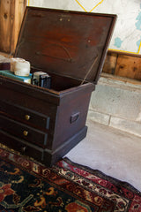 Dark wood antique cabinet side with handle, adjacent to a patterned blue Hamadan rug.